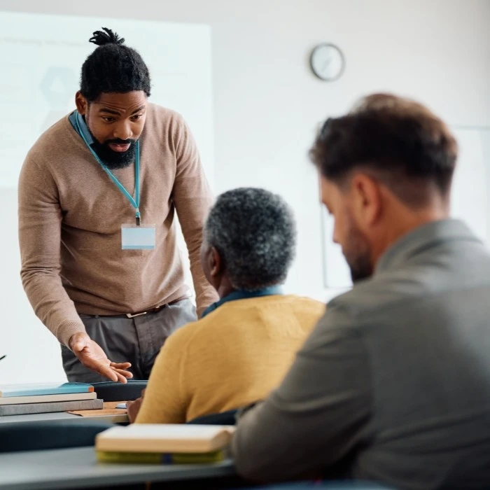 Black teacher talking to a senior man during an adult training session for the San Diego Regional Alliance for Fair Housing