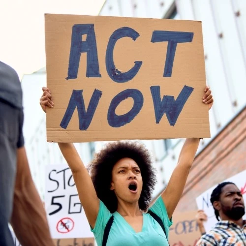 woman holding a big “Act Now” sign in San Diego
