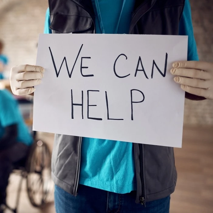 volunteer-holding-sign-that-says-we-can-help